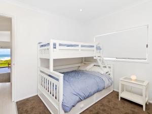 een wit stapelbed in een witte kamer met een raam bij Comfy Beachfront Unit, Unbeatable Location & Views in Avoca Beach