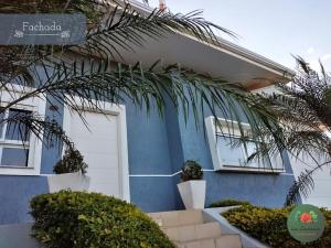 a blue house with a palm tree in front of it at Pousada La Casona in Tibagi