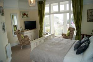 a bedroom with a bed and a tv and a window at Sunset Guest House in Hunstanton