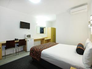 a hotel room with a bed and a desk with a computer at Airway Motel in Brisbane