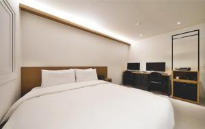 1 dormitorio con 1 cama blanca grande y escritorio en Busan Seomyeon Business Hotel J7, en Busan