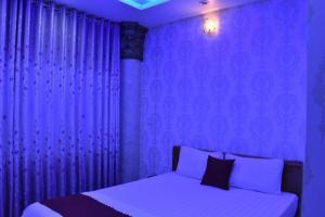 um quarto roxo com uma cama com cortinas roxas em Thien Phu Hotel em Ho Chi Minh