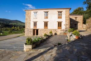 una vecchia casa in pietra con un vialetto in pietra di La Casona de Amaido a San Tirso de Abres