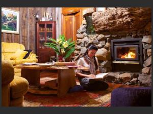 a woman sitting at a table in front of a stone fireplace at Tamborine Mountain Bed and Breakfast in Mount Tamborine