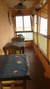 un balcone con 2 tavoli, sedie e finestre. di Sunrise Lodge a Varanasi