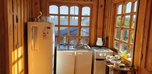 a kitchen with a refrigerator and a sink and windows at Cabañas cerca de Valdivia, en San José de la Mariquina in San José de la Mariquina