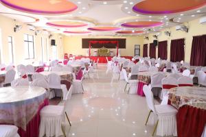 een banketzaal met witte tafels en stoelen en een podium bij Hotel the Narayani in Maruwā Ghāt