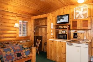 a bedroom with a bed and a kitchen in a cabin at Teton Valley Cabins in Driggs