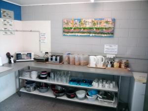 a kitchen with a shelf with cups and dishes at Bushchooks Travellers Village in Bororen