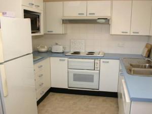 a kitchen with white cabinets and a stove and a sink at Charming Beach Getaway, Close to Cafe & Restaurant in Terrigal