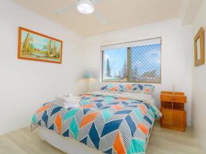 a bedroom with a colorful bed and a window at Acacia Holiday Apartment in Kingscliff