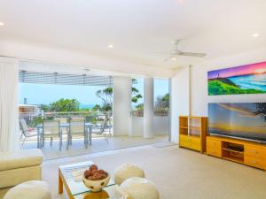 a living room with a large tv and a couch at Azura Ocean View Holiday Apartment in Kingscliff