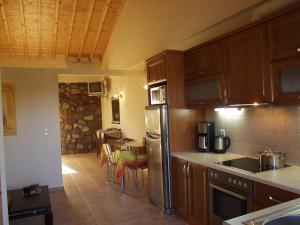 a kitchen with wooden cabinets and a dining room with a table at Michaela Beach Houses in Mythimna