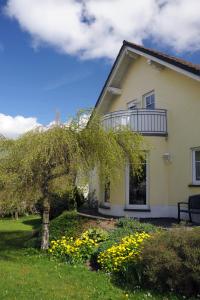 ein Haus mit einem Baum und gelben Blumen im Hof in der Unterkunft Ferienwohnung Landfein Schalkenmehren in Schalkenmehren