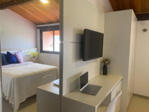 a bedroom with a bed and a desk with a laptop at Oka Muro Alto in Porto De Galinhas
