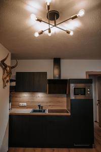 cocina con armarios negros, fregadero y techo en House 55, en Sölden