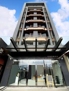 a tall apartment building with a glass window at Champ De Rose Hotel in Hualien City
