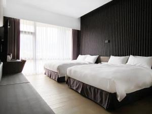 a hotel room with two beds and a large window at Champ De Rose Hotel in Hualien City