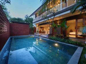 a swimming pool in front of a house at Agra & Amurti Villas in Munggu