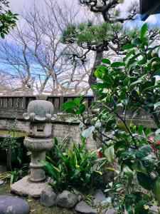 a stone statue in a garden in front of a fence at Guesthouse Sakichi in Beppu