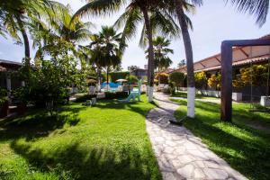 einen Garten mit Palmen und einem Gehweg in der Unterkunft Pousada Do Inglês in Jacumã