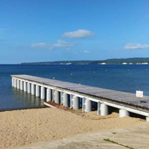 un muelle en la playa con el agua en ホステルたつみや en Sado