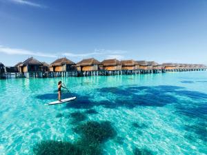 a woman on a paddle board in the ocean at Constance Moofushi Maldives - All Inclusive in Himandhoo 