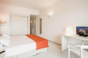 Schlafzimmer mit einem Bett, einem Schreibtisch und einem TV in der Unterkunft Minura Sur Menorca & Waterpark in Punta Prima