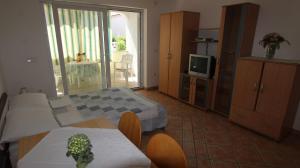 een kamer met een bed, een tafel en een televisie bij Apartments Grahovac in Malinska