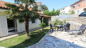 a patio with a palm tree and a table and chairs at Apartments Grahovac in Malinska