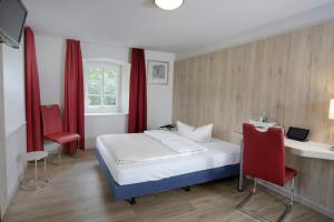 a bedroom with a bed and a desk and red curtains at Landidyll Hotel Erbgericht Tautewalde in Wilthen