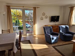 a living room with two blue chairs and a television at Hotel Seelust in Hohwacht