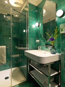 La salle de bains est pourvue de carrelage vert, d'un lavabo et d'une douche. dans l'établissement Le Katorze Hôtel, à Paris