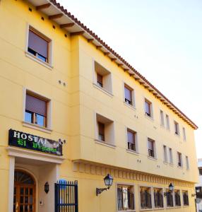 um grande edifício amarelo com um sinal nele em Hostal El Vegano em Utiel