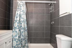 a bathroom with a shower curtain and a toilet at The Eastside Manor- With Private Yard & Free Parking, Minutes From Falls & Casino by Niagara Hospitality in Niagara Falls
