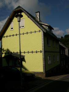 una casa amarilla con un cuadro a un lado. en Ferienwohnung Klaus im Tal der Steinach, en Steinach
