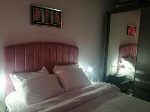 a bedroom with a bed with a pink headboard and a mirror at Porto Said in Port Said