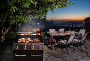 grill z jedzeniem na nim obok stołu w obiekcie Villa Erifili by Pelion Esties w mieście Agios Georgios Nilias