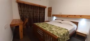 a small bedroom with a bed and a desk at Greenberg cottages Mararikulam in Mararikulam
