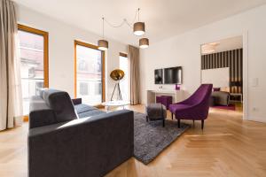 een woonkamer met een zwarte bank en paarse stoelen bij Modernes Apartment am Neumarkt in Dresden
