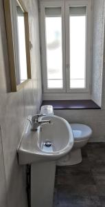 a bathroom with a sink and a toilet with two windows at Location G&W, très proche sanctuaires in Lourdes