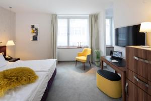 a hotel room with a bed and a desk and a television at Hotel Krone ****S in Tübingen