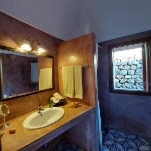 un bagno con lavandino, specchio e finestra di Agricola Pineda a Pantelleria