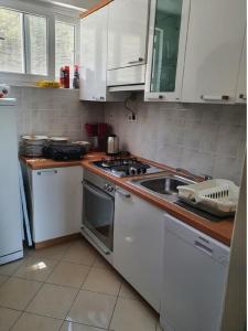 a kitchen with white cabinets and a stove and a sink at Apartments Elli in Korčula