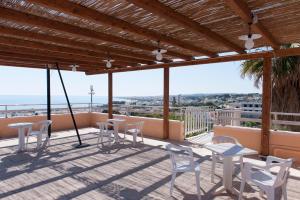 a patio with white chairs and tables on a balcony at Hotel La Collinetta in Torre Vado