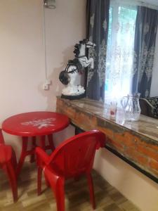 a red table and a red chair next to a window at House by the river in Martvili