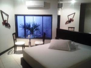 ein Schlafzimmer mit einem Bett und einem großen Fenster in der Unterkunft Toulouse Motel (Adult Only) in Natal