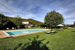 a swimming pool in a yard with chairs and an umbrella at Agriturismo il Corniolo in Cenerente