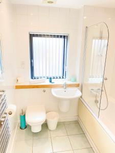 a white bathroom with a toilet and a sink at Tudors eSuites Spacious City Centre Apartment in Birmingham
