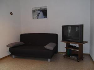 sala de estar con sofá negro y TV en Ferienhaus und Ferienwohnung Knappstein, en Möhnesee